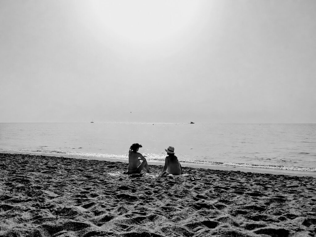 Two women chatting in the beach with a extraordinary sun light.