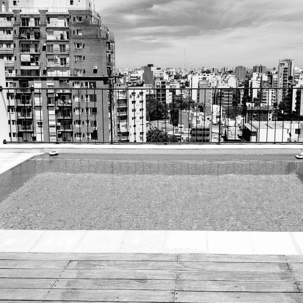 Rooftop pool overlooking a dense city skyline, black and white urban geometry photography